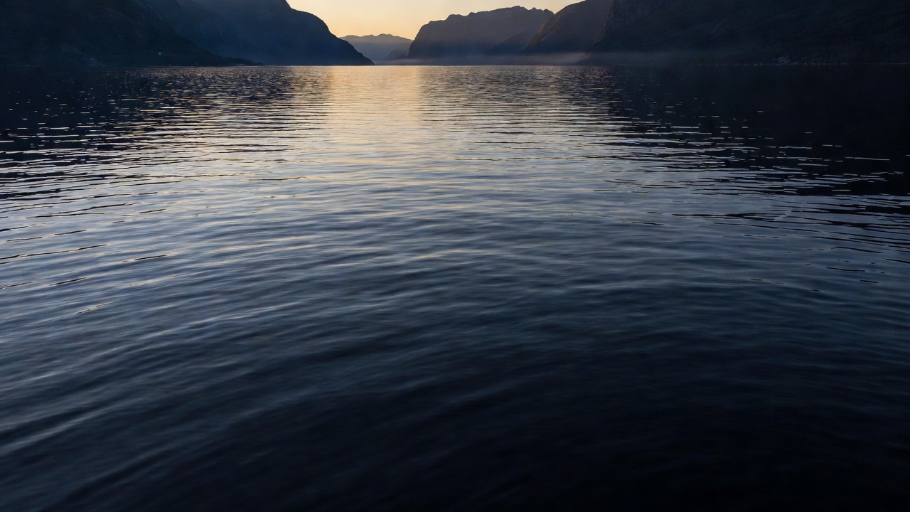 Soft evening light catching fine ripples on a dark fjord surface